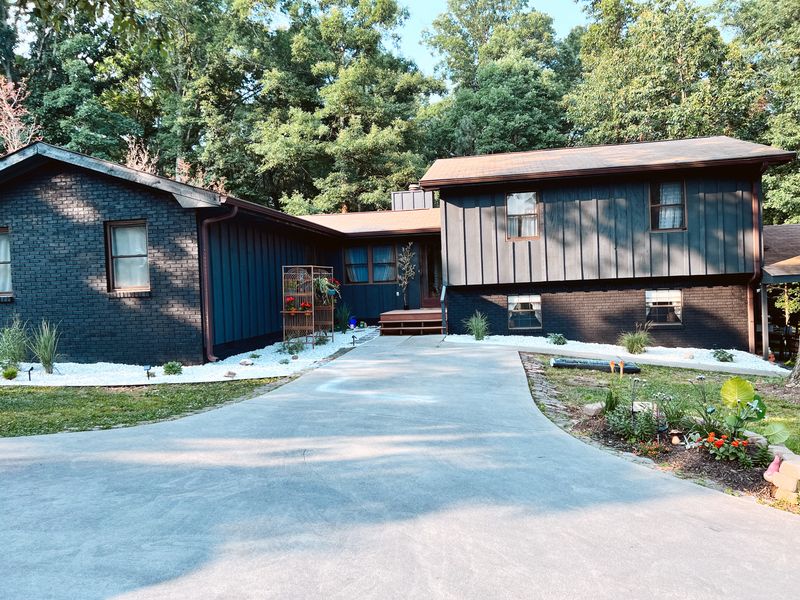 House exterior repainted dark navy and charcoal, seen from the driveway