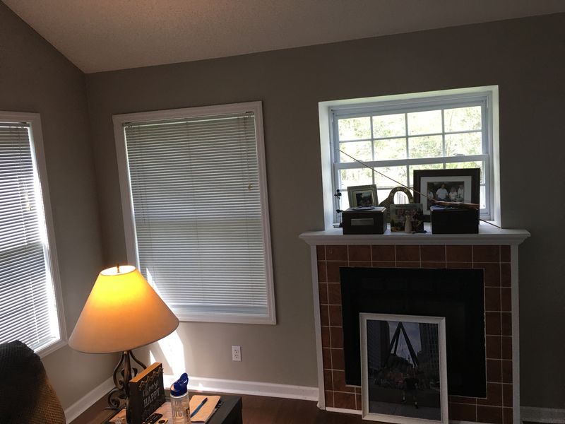 Living room with gray painted walls, white window trim and a brick fireplace