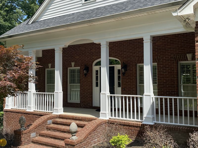 Brick home front porch with white columns and railings